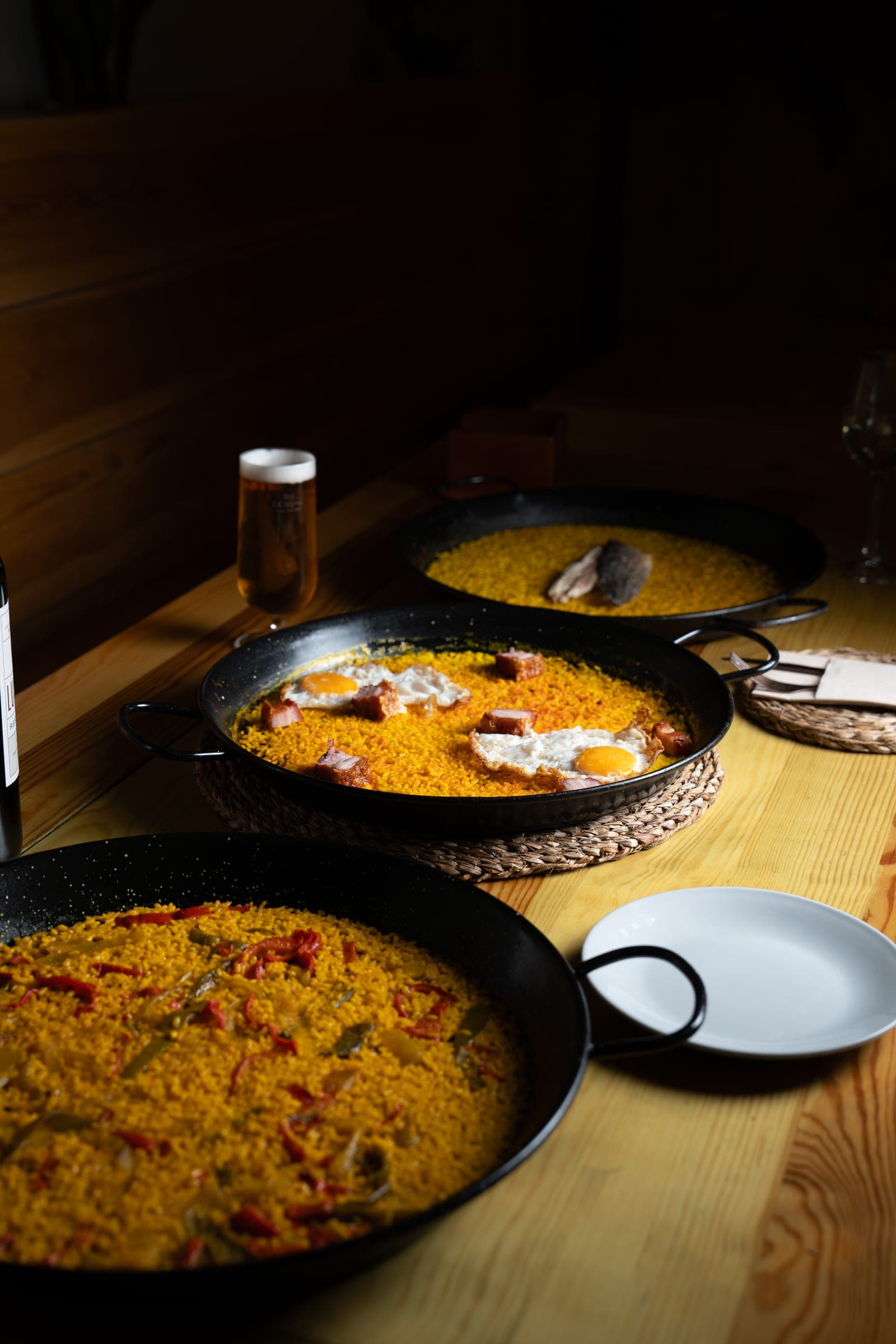 Mesa montada con paella, copa de vino y plato auxiliar bajo luz cálida